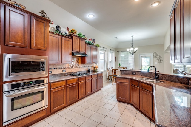 216 Barkley Dr, Hickory Creek, TX 75065 - kitchen with appliances with stainless steel finishes, light tile patterned floors, a chandelier, tasteful backsplash, and dark stone countertops