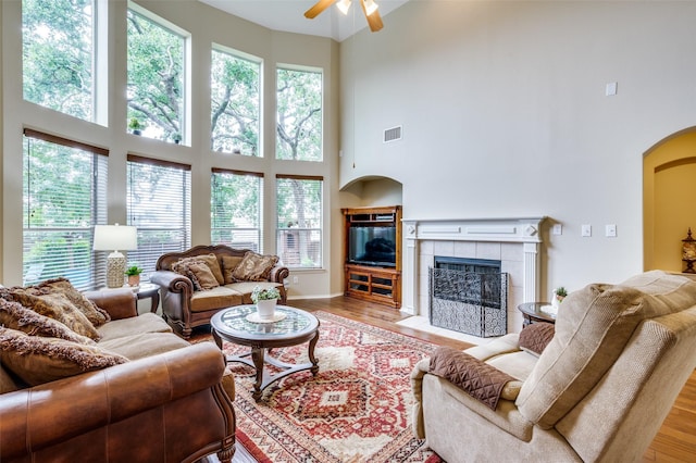 216 Barkley Dr, Hickory Creek, TX 75065 - living room with a towering ceiling, a tile fireplace, ceiling fan, arched walkways, and wood finished floors