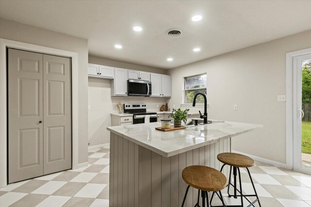 1716 Cordell St, Denton, TX 76201 - kitchen with stainless steel appliances, light stone counters, recessed lighting, light floors, and white cabinets