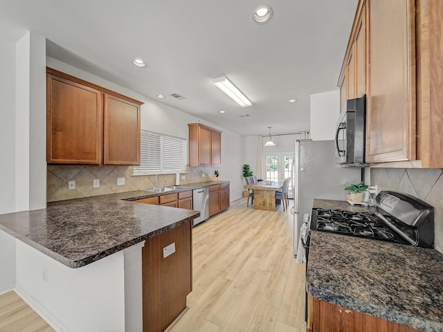 2021 Prospect Ln, Providence Village, TX 76227 - kitchen with dishwasher, black microwave, a peninsula, light wood-style floors, and decorative backsplash
