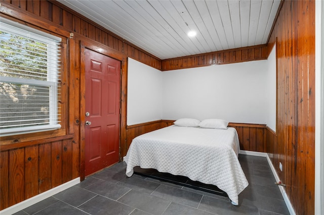 82 Vaughn Dr, Denison, TX 75020 - bedroom featuring wooden walls, a wainscoted wall, wooden ceiling, and dark tile patterned floors