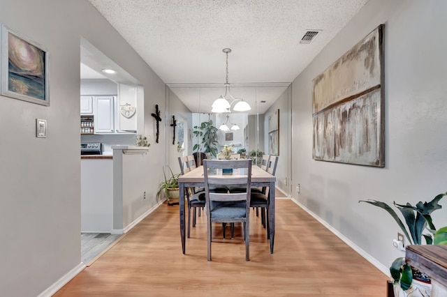 3003 Rustling Leaves Ln, Bedford, TX 76021 - dining space with light wood-style floors, a textured ceiling, and a chandelier
