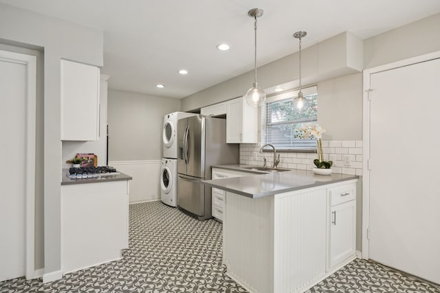 11335 Fernald Ave, Dallas, TX 75218 - kitchen featuring stacked washing machine and dryer, white cabinets, a peninsula, a wainscoted wall, and decorative backsplash