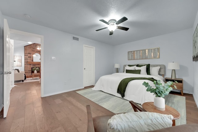 1024 E Peters Colony Rd, Carrollton, TX 75007 - bedroom featuring wood finished floors, a ceiling fan, and a large fireplace
