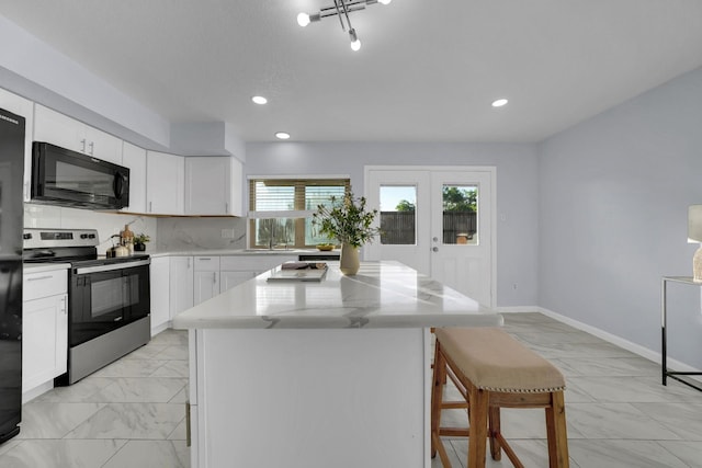 1024 E Peters Colony Rd, Carrollton, TX 75007 - kitchen with black appliances, light marble finish floors, a breakfast bar area, a center island, and white cabinets