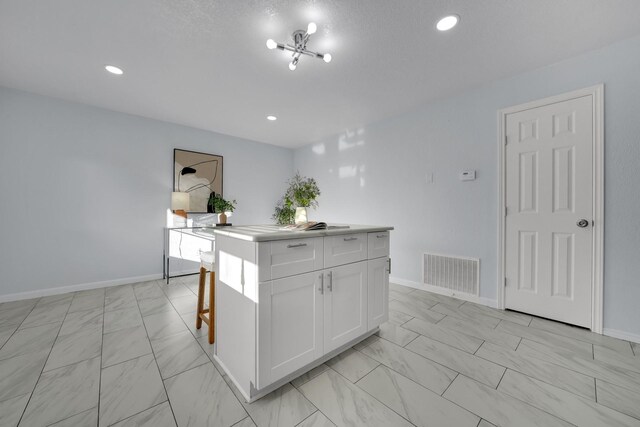 1024 E Peters Colony Rd, Carrollton, TX 75007 - kitchen featuring light marble finish flooring, white cabinets, a kitchen island, recessed lighting, and light countertops