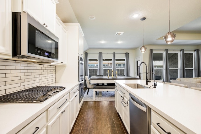 8116 Charford Dr, Fort Worth, TX 76131 - kitchen with appliances with stainless steel finishes, light countertops, dark wood finished floors, white cabinetry, and decorative light fixtures