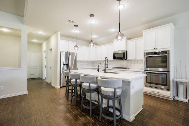 8116 Charford Dr, Fort Worth, TX 76131 - kitchen with appliances with stainless steel finishes, dark wood-style floors, decorative backsplash, light countertops, and a center island with sink