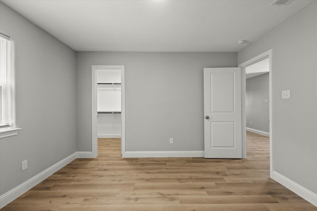 6311 Pebble Ave, Dallas, TX 75217 - unfurnished bedroom featuring light wood-style floors, a walk in closet, and a closet