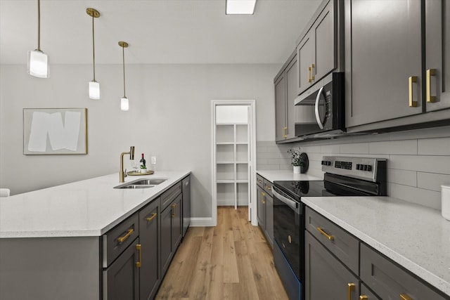 6311 Pebble Ave, Dallas, TX 75217 - kitchen with stainless steel appliances, a peninsula, backsplash, and light wood finished floors