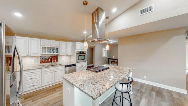 2305 Briarwood Ln, Carrollton, TX 75006 - kitchen featuring stainless steel appliances, island exhaust hood, a kitchen island, light wood finished floors, and vaulted ceiling