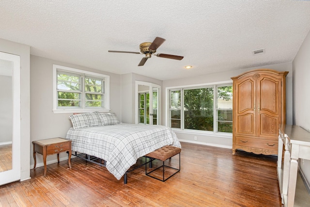 567 Peavy Rd, Dallas, TX 75218 - bedroom with wood finished floors, multiple windows, a textured ceiling, and a ceiling fan