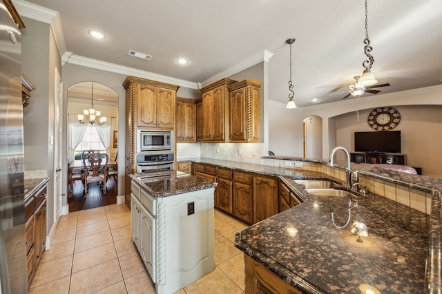 1535 Winding Creek Ln, Rockwall, TX 75032 - kitchen featuring arched walkways, appliances with stainless steel finishes, crown molding, brown cabinetry, and a chandelier