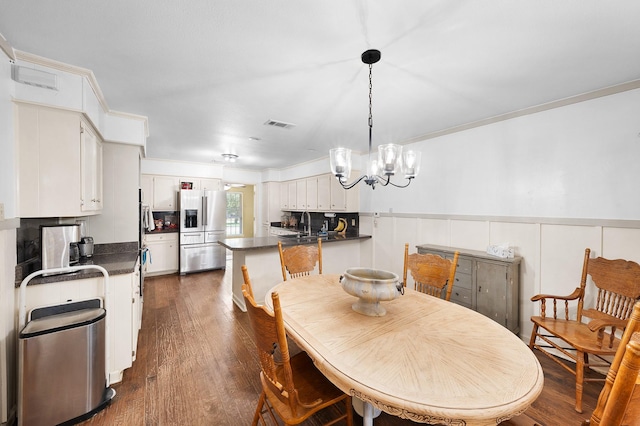 1440 Live Oak St, Sulphur Springs, TX 75482 - dining space featuring a chandelier, dark wood-style floors, wainscoting, and ornamental molding
