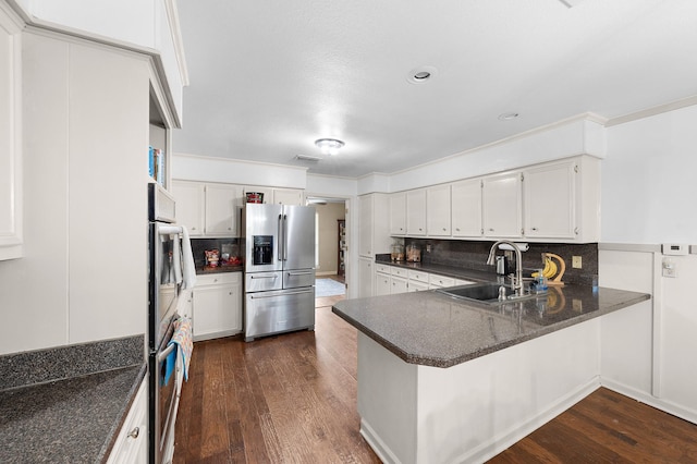 1440 Live Oak St, Sulphur Springs, TX 75482 - kitchen featuring appliances with stainless steel finishes, tasteful backsplash, dark wood-style floors, a peninsula, and white cabinets