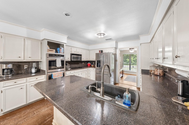 1440 Live Oak St, Sulphur Springs, TX 75482 - kitchen featuring stainless steel appliances, a peninsula, dark countertops, white cabinetry, and crown molding