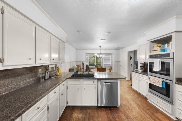 1440 Live Oak St, Sulphur Springs, TX 75482 - kitchen with appliances with stainless steel finishes, a peninsula, white cabinetry, a chandelier, and dark wood-type flooring