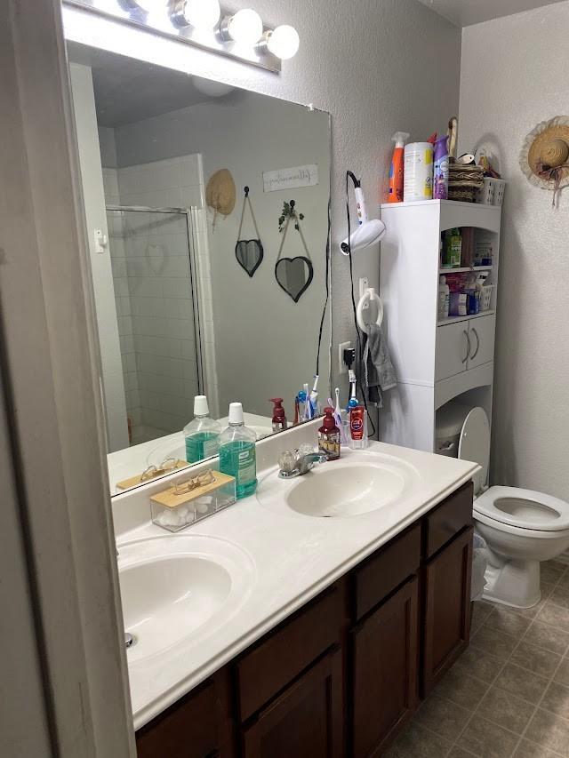253 Pine Crest Dr, Justin, TX 76247 - bathroom featuring a stall shower, double vanity, a textured wall, and tile patterned flooring