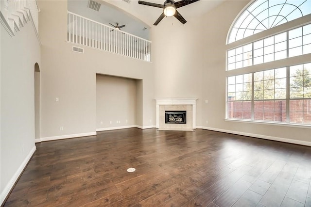 9204 Bottlebrush Ln, Irving, TX 75063 - unfurnished living room featuring a ceiling fan, dark wood finished floors, a towering ceiling, a high end fireplace, and arched walkways