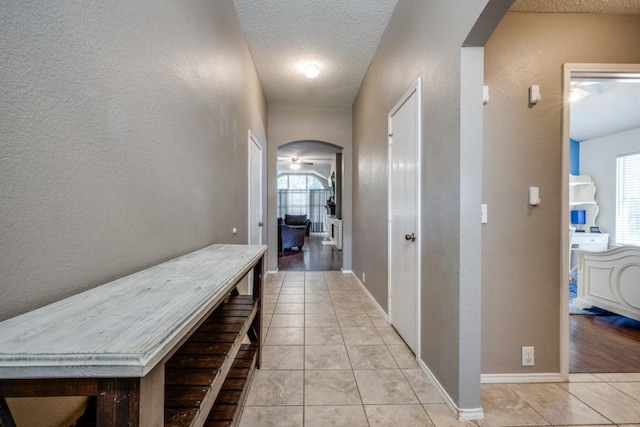 726 Texas Oak Trl, Lake Dallas, TX 75065 - corridor featuring arched walkways, a textured wall, a textured ceiling, and light tile patterned flooring