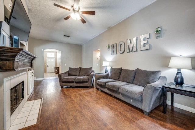 726 Texas Oak Trl, Lake Dallas, TX 75065 - living room with ceiling fan, arched walkways, wood finished floors, a fireplace, and a textured ceiling