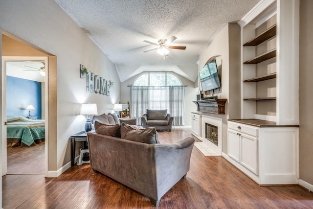 726 Texas Oak Trl, Lake Dallas, TX 75065 - living room featuring a ceiling fan, a fireplace with flush hearth, dark wood finished floors, a textured ceiling, and lofted ceiling