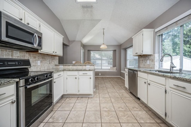 726 Texas Oak Trl, Lake Dallas, TX 75065 - kitchen featuring stainless steel appliances, white cabinetry, lofted ceiling, a peninsula, and backsplash