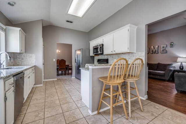 726 Texas Oak Trl, Lake Dallas, TX 75065 - kitchen with stainless steel appliances, light tile patterned flooring, a peninsula, white cabinets, and tasteful backsplash