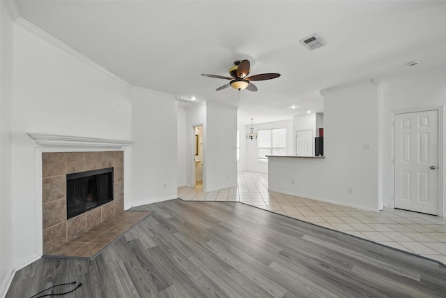 9846 Cedarcrest Dr, Providence Village, TX 76227 - unfurnished living room featuring ceiling fan, a fireplace, crown molding, light wood-style floors, and a chandelier