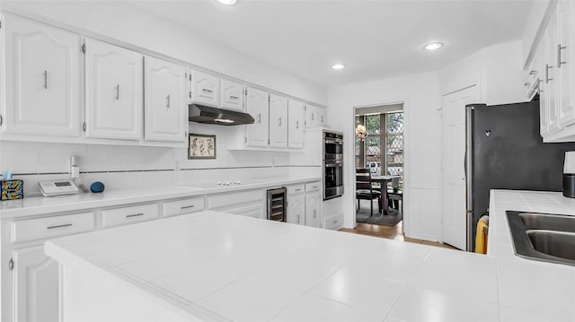 3705 Starlight Trl, Plano, TX 75023 - kitchen with under cabinet range hood, white cabinets, wine cooler, decorative backsplash, and recessed lighting