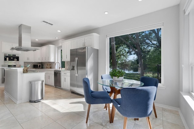 7955 Enclave Way, Dallas, TX 75218 - kitchen with stainless steel appliances, island exhaust hood, light countertops, white cabinetry, and tasteful backsplash