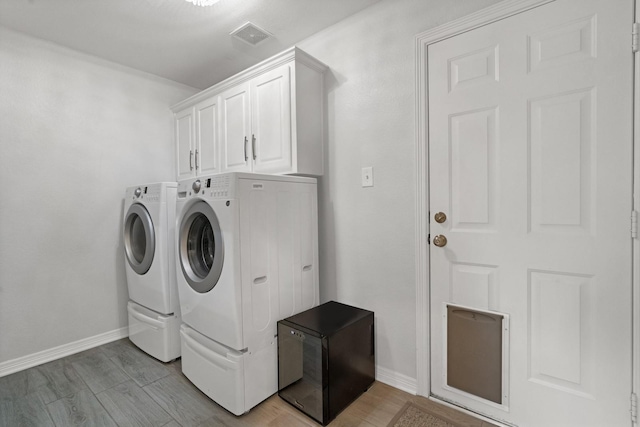 7955 Enclave Way, Dallas, TX 75218 - laundry area with washing machine and clothes dryer, cabinet space, and light wood-style floors