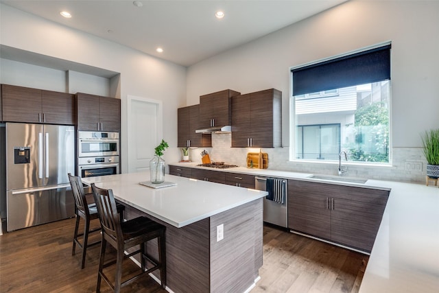 381 E Greenbriar Ln Unit 501, Dallas, TX 75203 - kitchen with stainless steel appliances, a kitchen breakfast bar, dark wood-style floors, backsplash, and recessed lighting