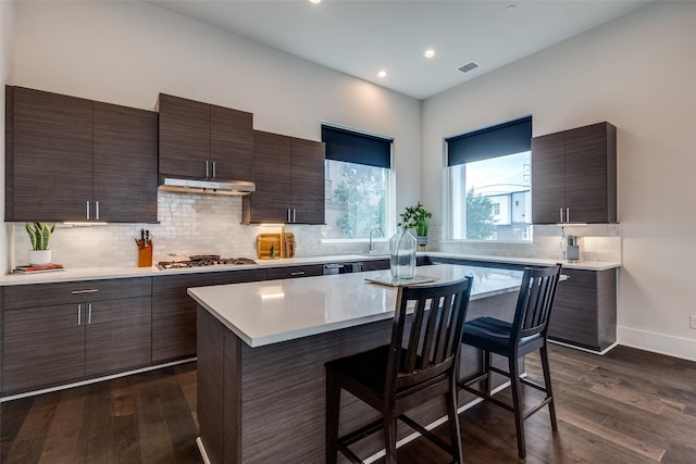 381 E Greenbriar Ln Unit 501, Dallas, TX 75203 - kitchen featuring a kitchen bar, light countertops, modern cabinets, stainless steel gas cooktop, and dark wood-style floors