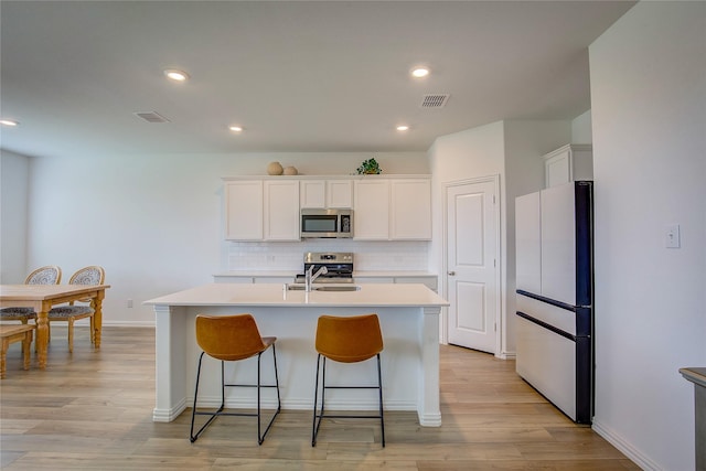 5221 Rockrose Ln, Princeton, TX 75407 - kitchen featuring stainless steel appliances, tasteful backsplash, a kitchen island with sink, light countertops, and white cabinetry