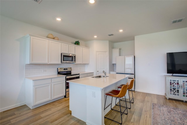 5221 Rockrose Ln, Princeton, TX 75407 - kitchen with stainless steel appliances, light wood-style flooring, white cabinets, backsplash, and a center island with sink