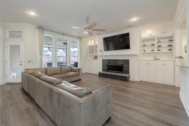 5729 Ridgehaven Dr, Plano, TX 75093 - living room with a ceiling fan, crown molding, a tile fireplace, wood finished floors, and built in features