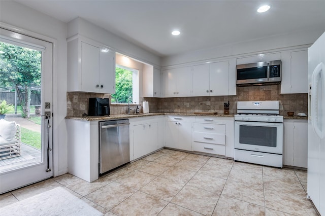 2811 Maple Springs Blvd, Dallas, TX 75235 - kitchen with stainless steel appliances, white cabinetry, decorative backsplash, light stone countertops, and recessed lighting
