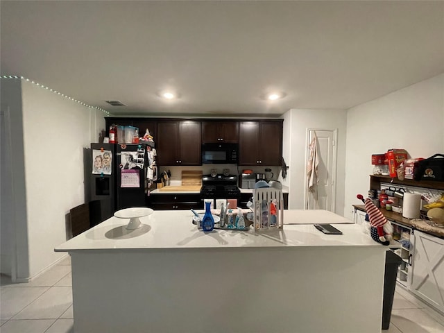 803 Odlozil Ln, Ennis, TX 75119 - kitchen with black appliances, light tile patterned floors, an island with sink, dark brown cabinets, and recessed lighting