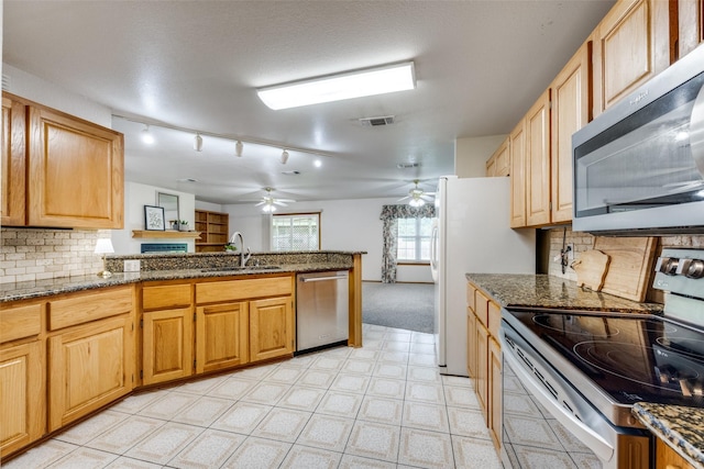 15 Cumberland Cir, Denison, TX 75021 - kitchen with appliances with stainless steel finishes, a ceiling fan, a peninsula, decorative backsplash, and dark stone countertops