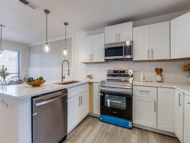 2614 San Saba St, Mesquite, TX 75150 - kitchen featuring appliances with stainless steel finishes, a peninsula, light wood-style floors, and white cabinets
