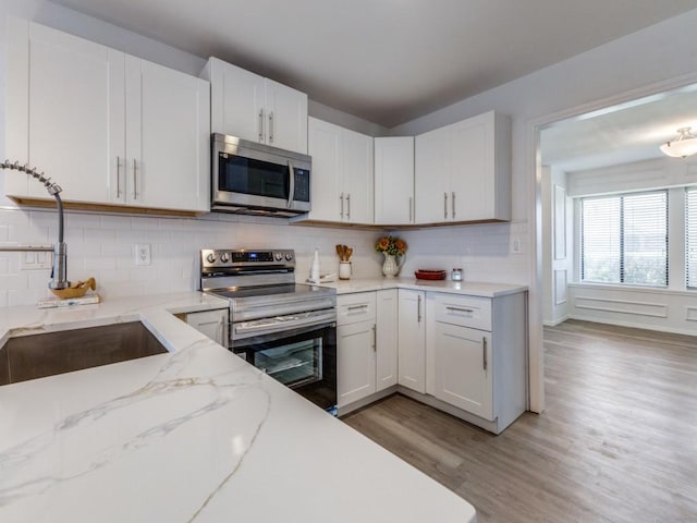 2614 San Saba St, Mesquite, TX 75150 - kitchen featuring stainless steel appliances, light wood-type flooring, decorative backsplash, and white cabinetry
