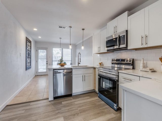 2614 San Saba St, Mesquite, TX 75150 - kitchen with stainless steel appliances, a peninsula, light countertops, decorative backsplash, and light wood-style floors