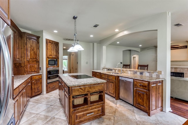 6707 Canyon Crest Dr, Fort Worth, TX 76132 - kitchen featuring appliances with stainless steel finishes, an island with sink, arched walkways, recessed lighting, and hanging light fixtures