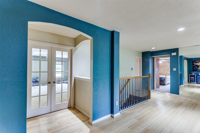 6707 Canyon Crest Dr, Fort Worth, TX 76132 - hallway featuring wood finished floors, an upstairs landing, arched walkways, french doors, and a textured wall