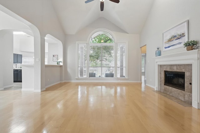 2402 Pittsburg Lndg, Mesquite, TX 75181 - unfurnished living room with a ceiling fan, light wood-type flooring, a tiled fireplace, and vaulted ceiling