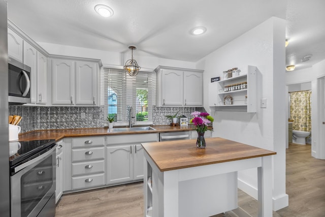 10917 Caldwell Ln, Fort Worth, TX 76179 - kitchen featuring wooden counters, appliances with stainless steel finishes, decorative backsplash, open shelves, and light wood-style flooring