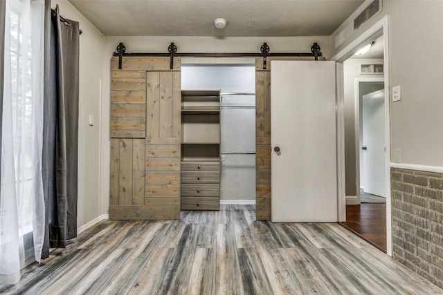 1614 Baltimore Dr, Richardson, TX 75081 - unfurnished bedroom with a barn door, wood finished floors, and a closet