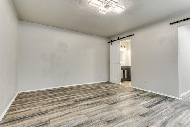 1614 Baltimore Dr, Richardson, TX 75081 - unfurnished room featuring a barn door, wood finished floors, and a textured ceiling