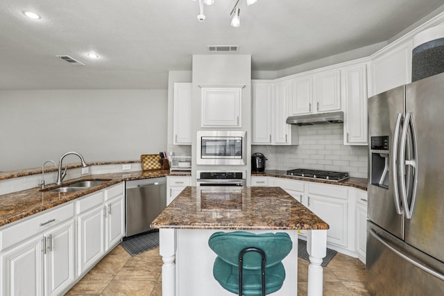 8729 Somerville Way, Plano, TX 75025 - kitchen featuring stainless steel appliances, white cabinetry, dark stone countertops, backsplash, and under cabinet range hood